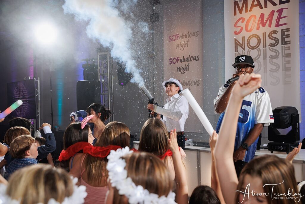 A Bar Mitzvah guest of honor using a T-shirt cannon to engage a high-energy crowd on the dance floor during a celebration in the DMV area.
