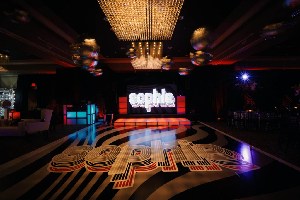 LED video wall displaying “Sophie” above an illuminated stage, with a matching personalized dance floor.